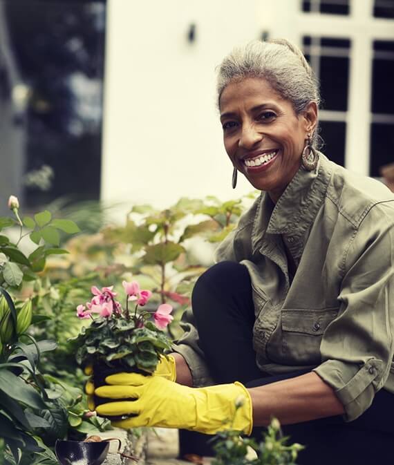 Happy retired senior woman gardening in back yard