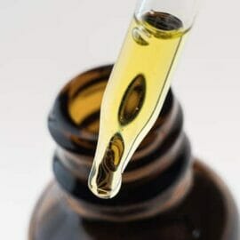 Close up of a container of CBD oil, with the dropper partially filled.