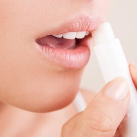A woman putting CBD lip balm onto her lips.