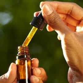 A dropper being used to extract some CBD tincture from its bottle.