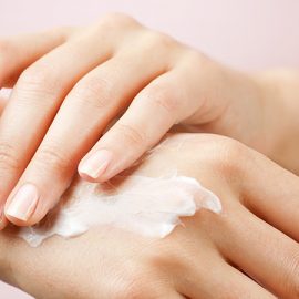 A woman rubbing CBD cream into the back of her right hand.
