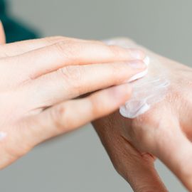 A woman rubbing CBD cream into the back of her left hand.