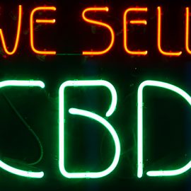Neon store sign reading "We Sell" in orange and "CBD" in green.
