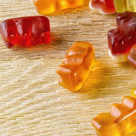 Several red, orange, and yellow gummies strewn across a table.